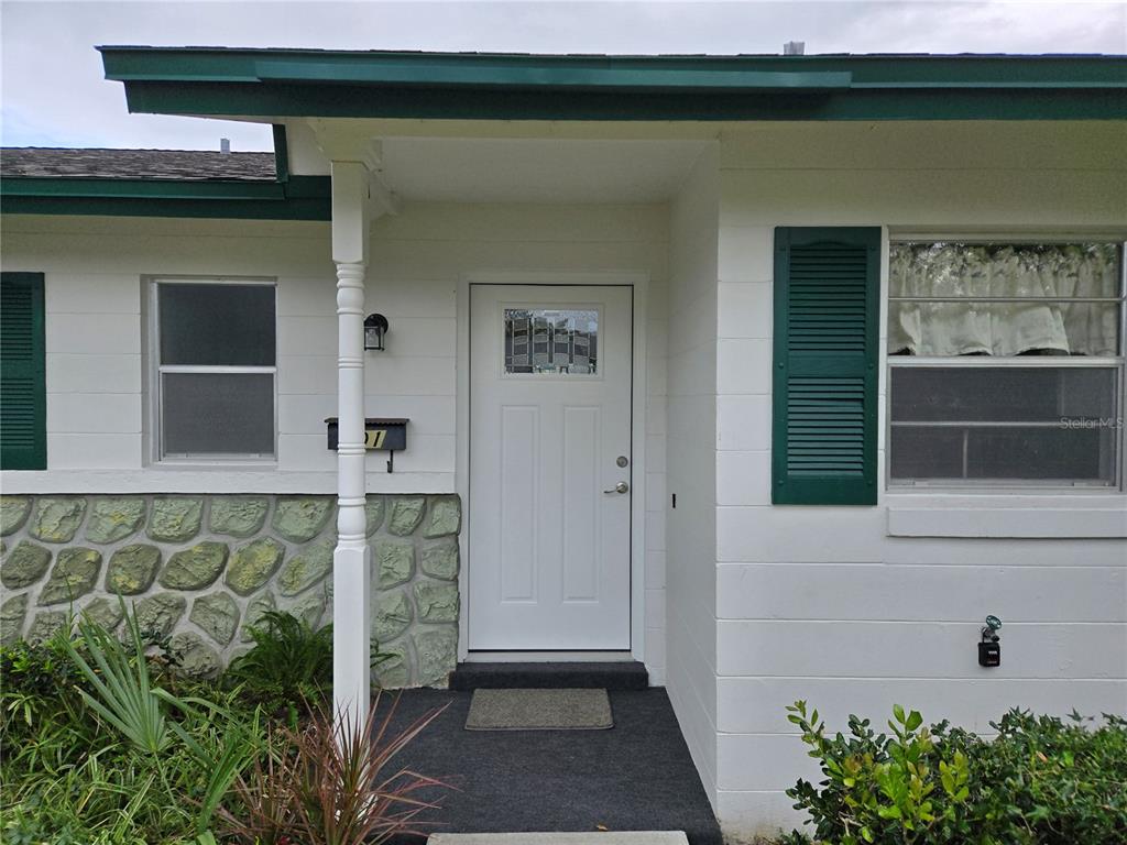 The front exterior of a house features a white door, green shutters, and stone siding — 201 N HILL AVENUE UNIT 150, DELAND, FL