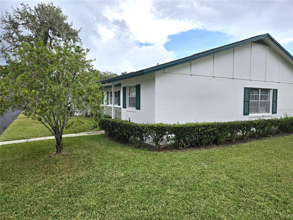A white, single-story house with green shutters and a hedge in the front yard — 201 N HILL AVENUE UNIT 150, DELAND, FL