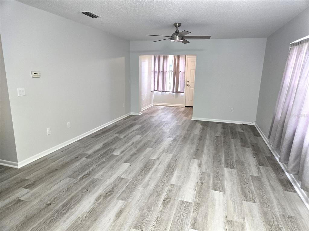 An empty living room features light gray walls, wood-look flooring, and a ceiling fan — 201 N HILL AVENUE UNIT 150, DELAND, FL