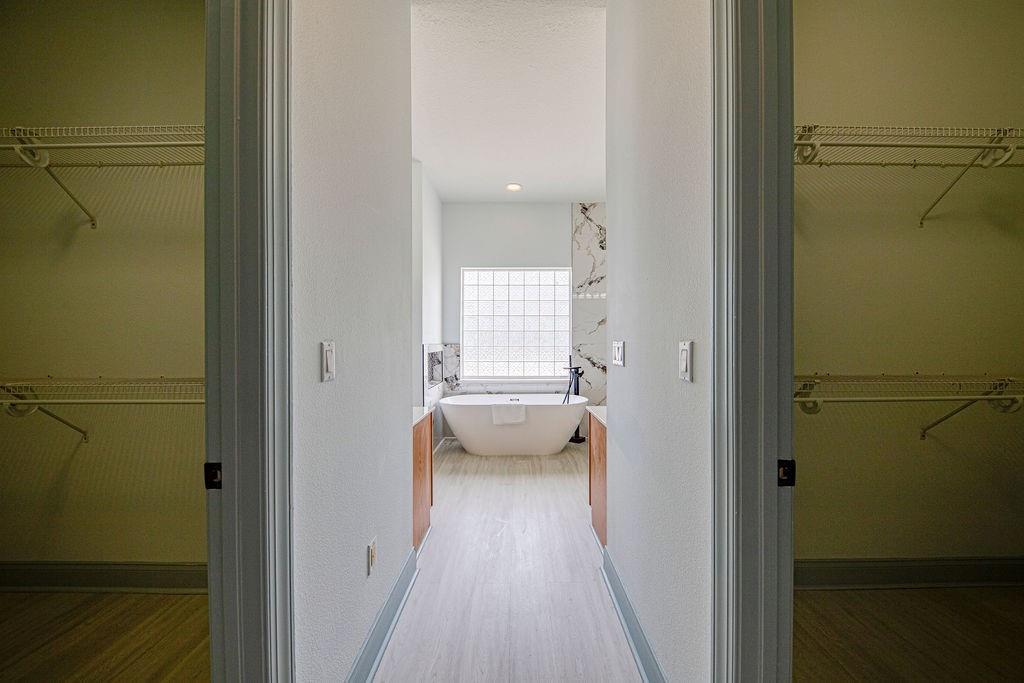 A hallway leads to a bathroom featuring a freestanding tub and a glass block window — 4873 NE 64th Avenue, FL 34488, FL