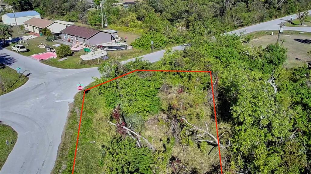 An aerial view shows a vacant, wooded lot outlined in red at a street intersection — 11272 7TH AVENUE, PUNTA GORDA, FL