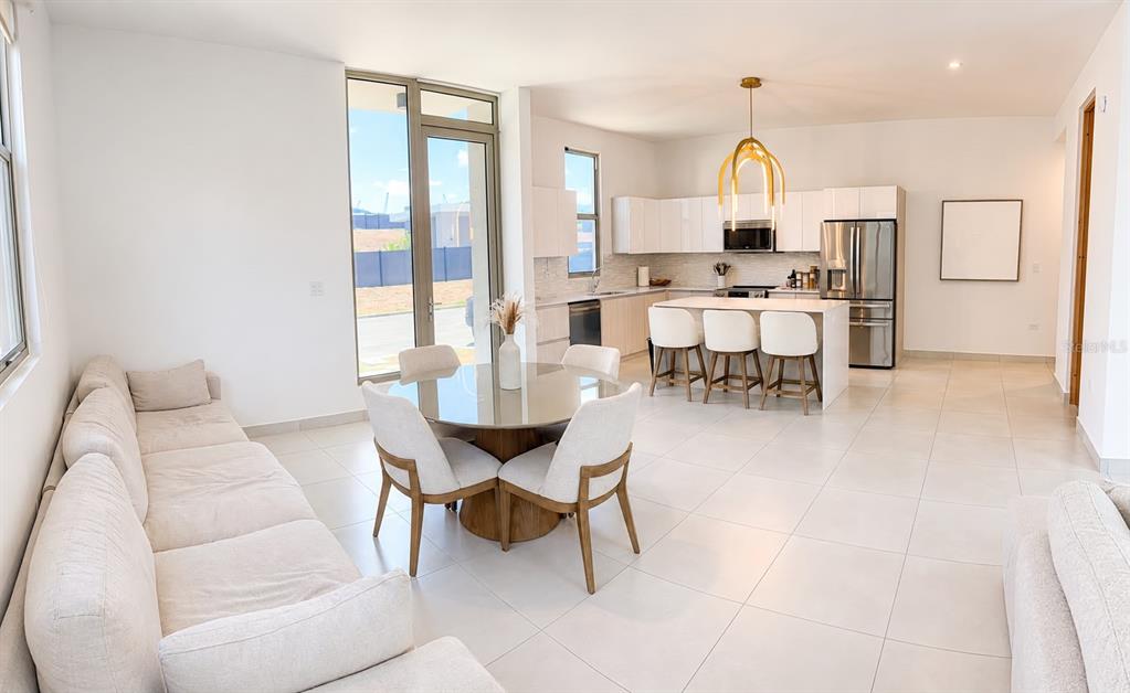 An open-concept living and dining area features a modern kitchen with white cabinetry and tile flooring — 110 St. RIVER VIEW CIUDAD JARDIN, GURABO, PR