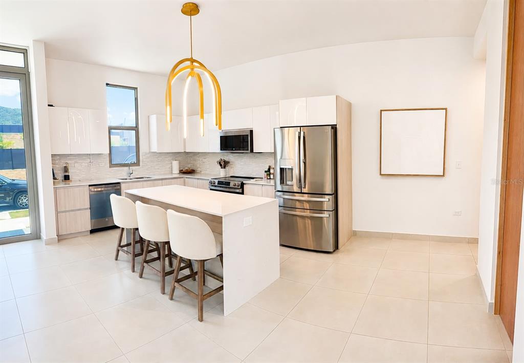 A modern kitchen features white cabinets, stainless steel appliances, a central island, and bar stools — 110 St. RIVER VIEW CIUDAD JARDIN, GURABO, PR