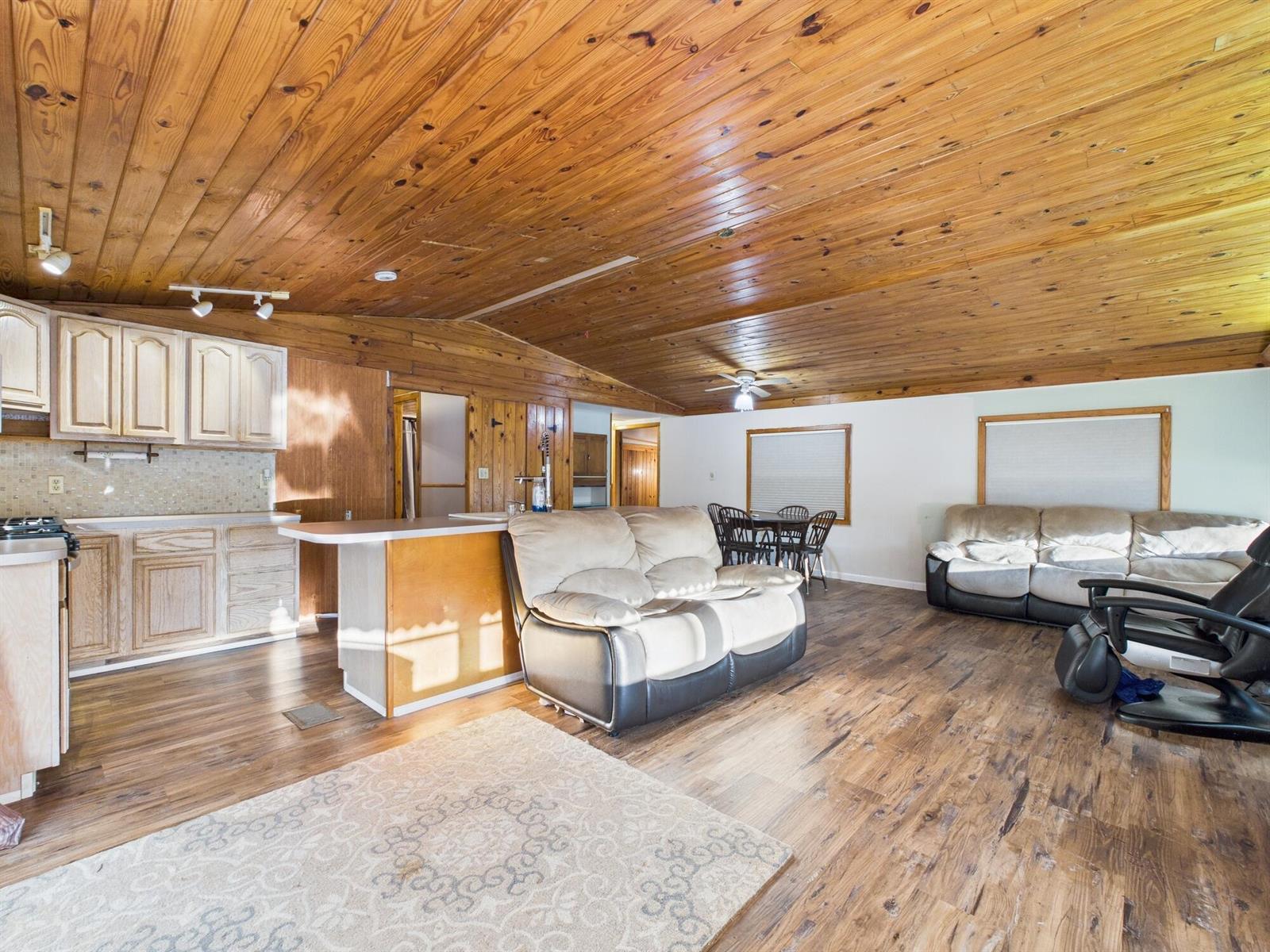 An open-concept living area features a kitchen, dining space, wood-paneled ceiling, and wood flooring — 56 Basin Street, FL 33857, FL