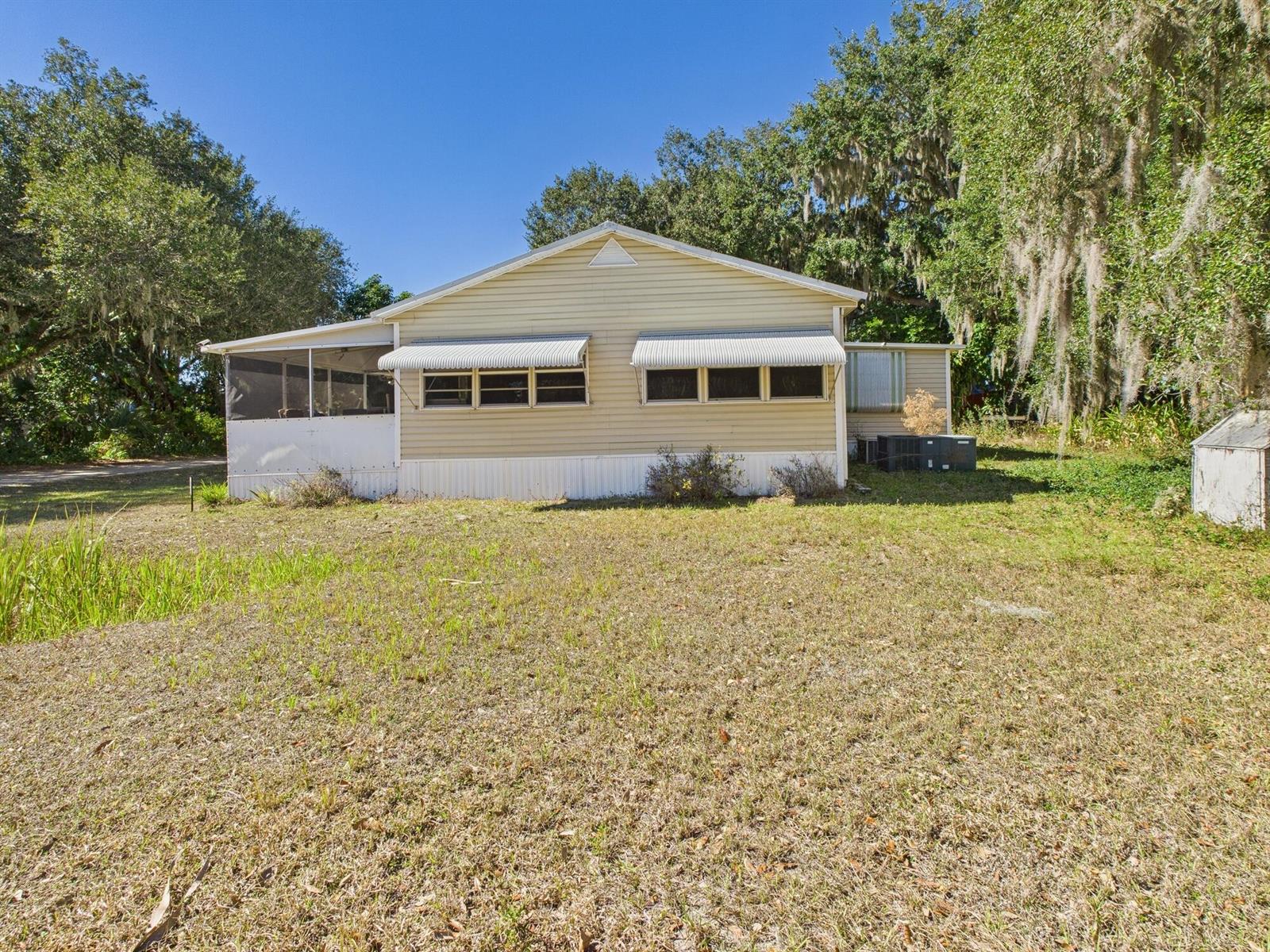 A single-story house with light-colored siding and a screened-in porch sits on a grassy lot — 56 Basin Street, FL 33857, FL