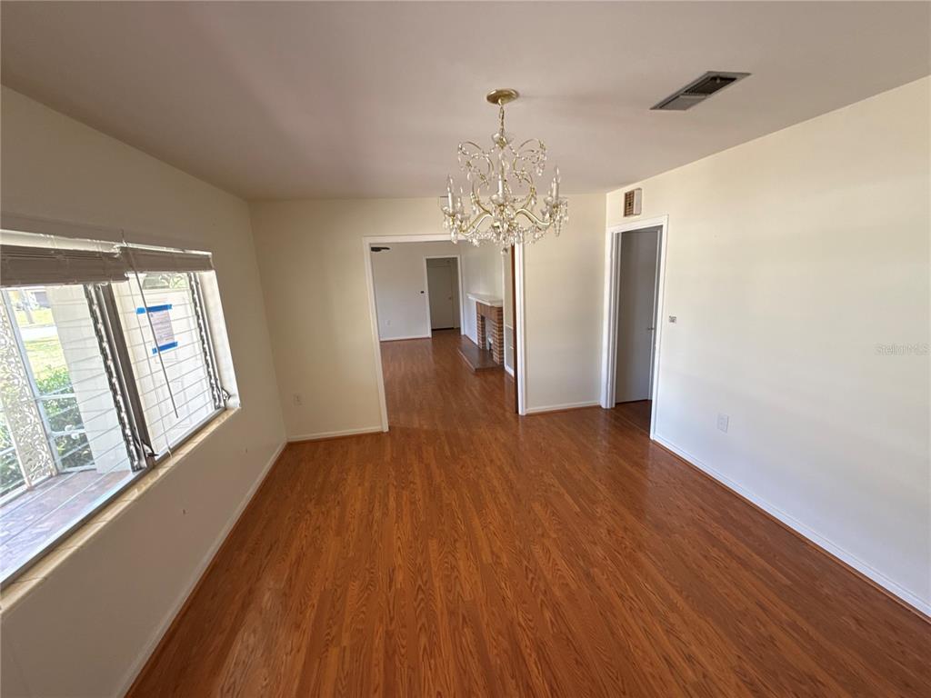 A dining room with wood flooring, a crystal chandelier, and a view into another room — 1485 DAVIS AVENUE, BARTOW, FL