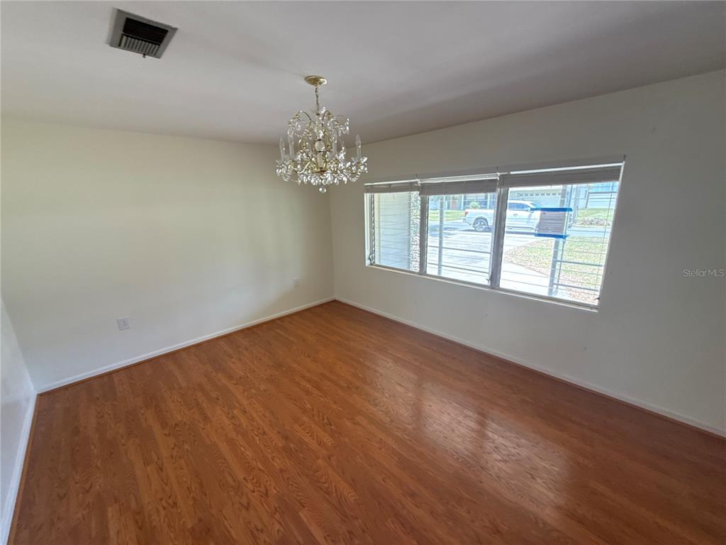 An empty dining room features hardwood floors, a crystal chandelier, and a large window — 1485 DAVIS AVENUE, BARTOW, FL