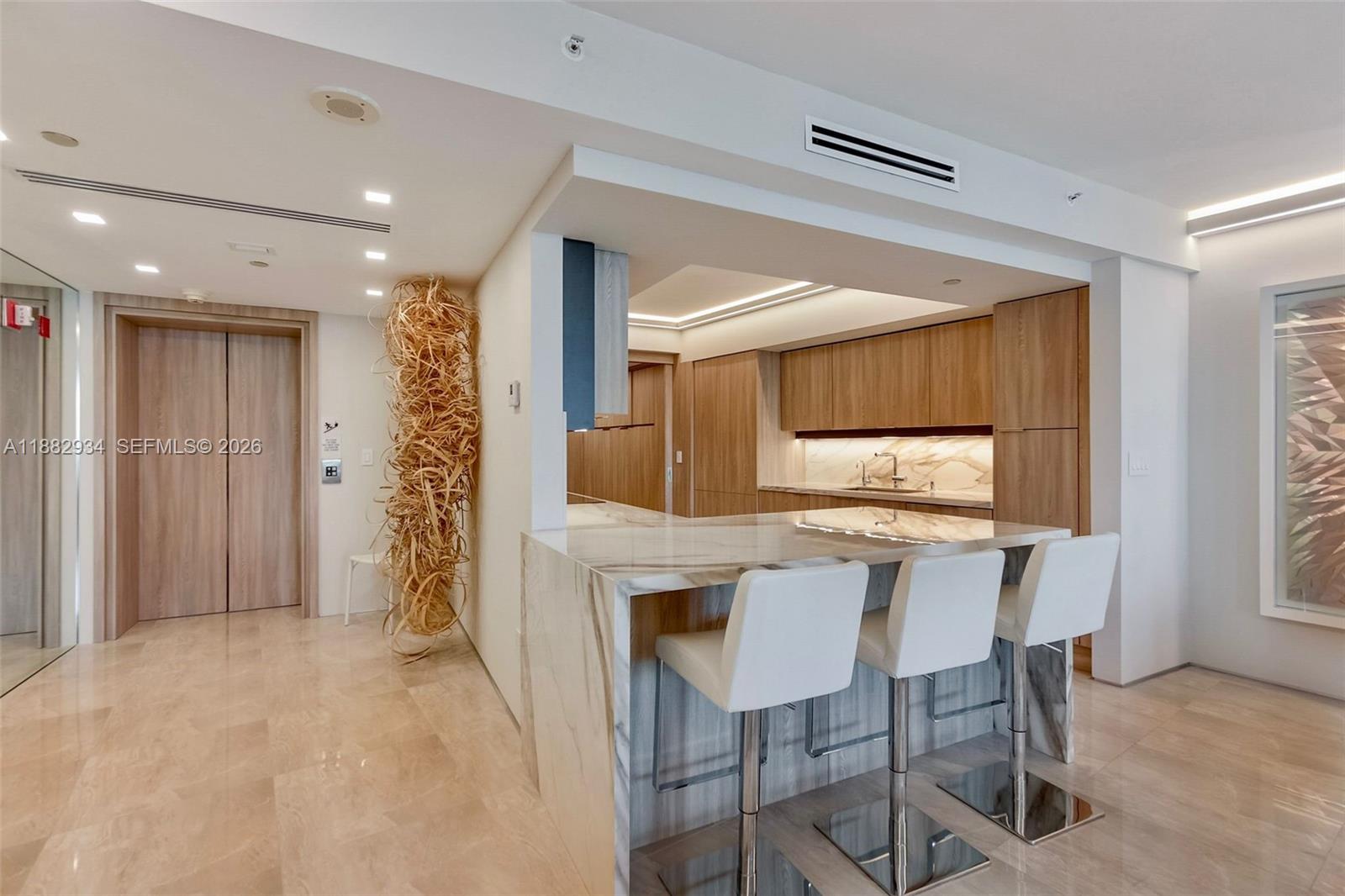 A modern living room features a beige sectional, white armchairs, and floor-to-ceiling windows — 1455 Ocean Dr # 811, Miami Beach FL 33139, MIAMI BEACH, FL