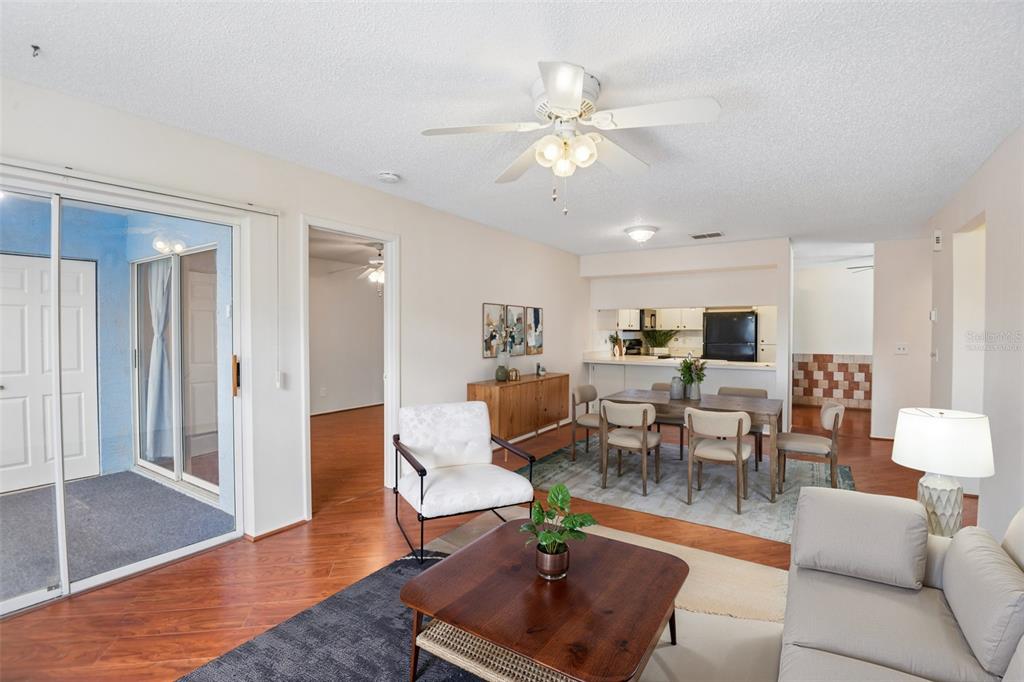 A living and dining area with wood floors, a ceiling fan, and a sliding glass door — 7713 HILLSIDE COURT UNIT 204, HUDSON, FL