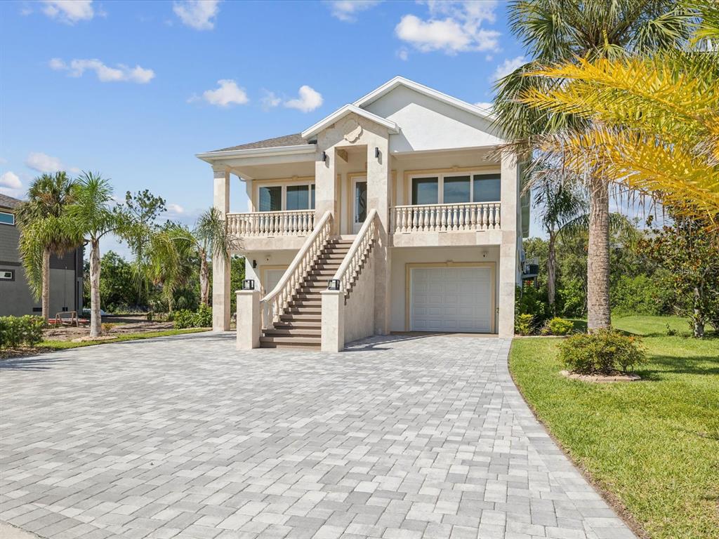 A two-story house with a raised entrance, stone facade, and a paved driveway — 5621 EGRETS PLACE, NEW PORT RICHEY, FL
