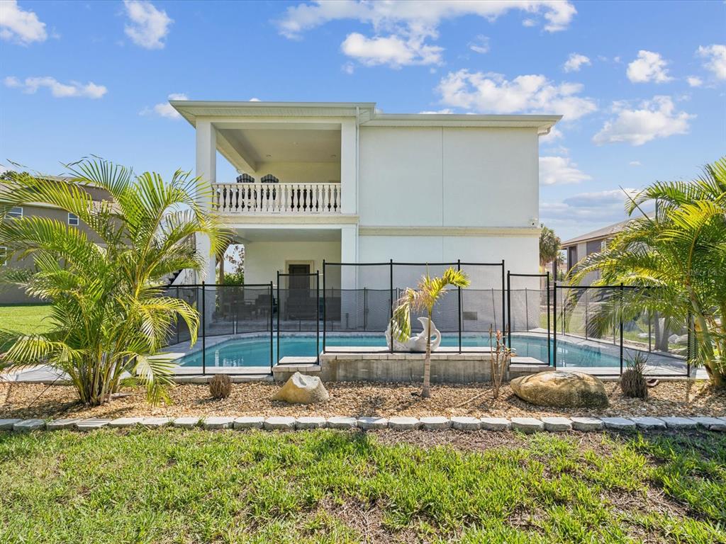 A two-story house features a backyard swimming pool enclosed by a black safety fence — 5621 EGRETS PLACE, NEW PORT RICHEY, FL
