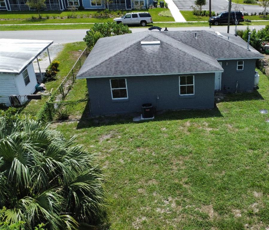 An aerial view shows the gray exterior of a house with a shingled roof — 3715 AVENUE J NW, WINTER HAVEN, FL