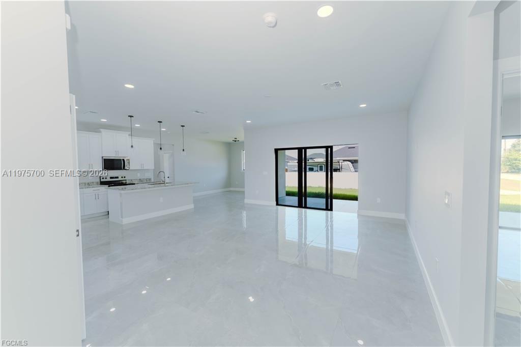 An open-concept kitchen and living area features white cabinetry, a kitchen island, and tile flooring — 4705 diane ave, Lehigh Acres FL 33976, LEHIGH ACRES, FL