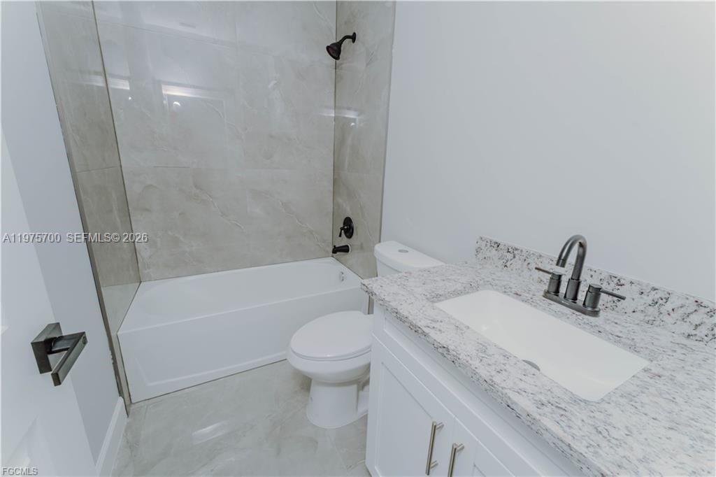 A bathroom features a white vanity with a granite countertop, a toilet, and a tub-shower — 4705 diane ave, Lehigh Acres FL 33976, LEHIGH ACRES, FL