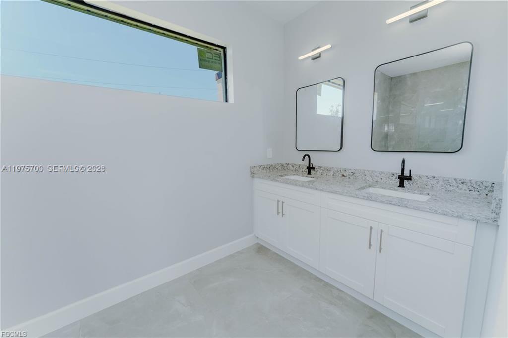 A modern bathroom features a double vanity with white cabinets and a granite countertop — 4705 diane ave, Lehigh Acres FL 33976, LEHIGH ACRES, FL