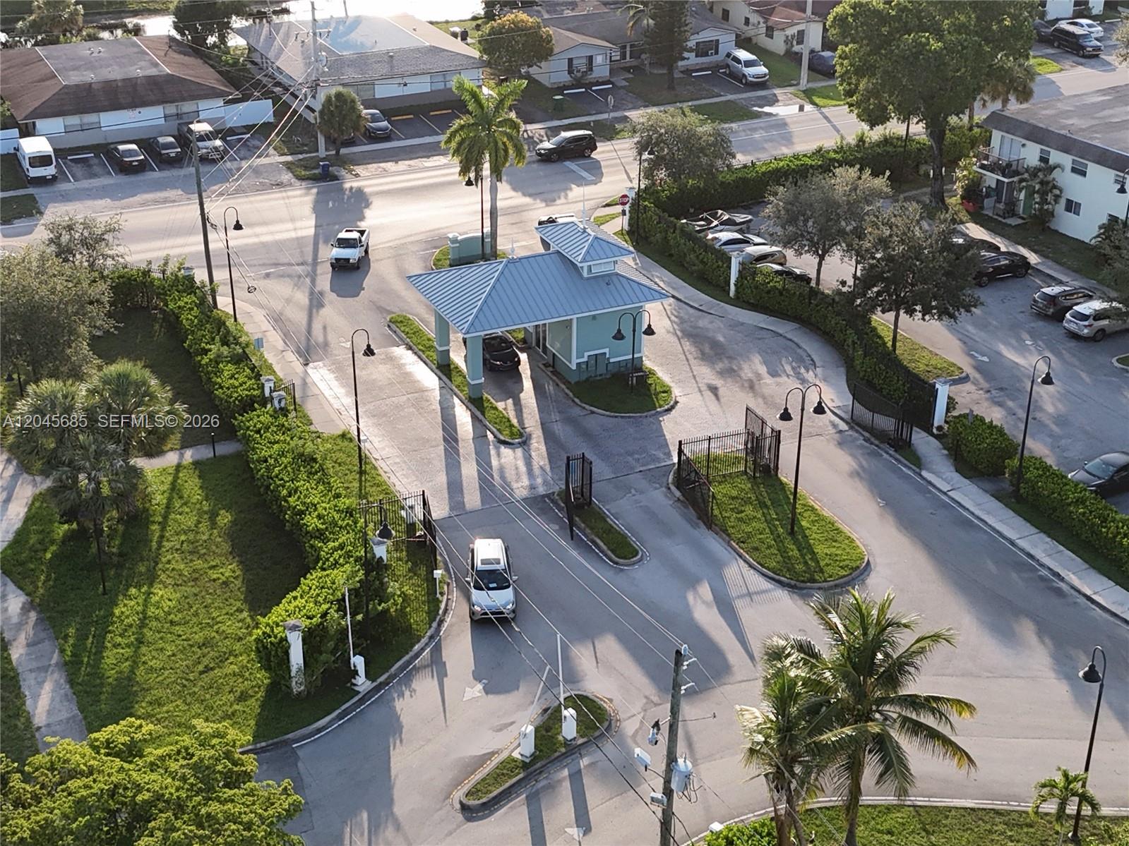 An aerial view shows a gated community entrance with a guardhouse and surrounding parking lots — 1796 NW 55th Ave # 103, Lauderhill FL 33313, LAUDERHILL, FL
