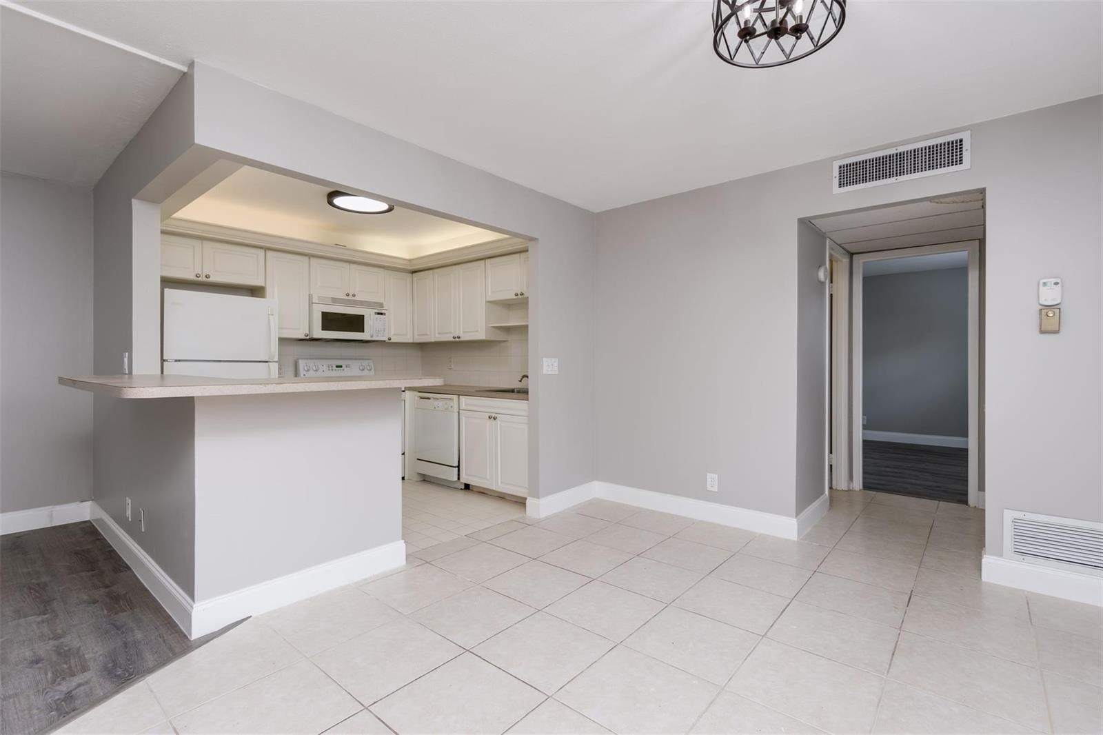 A kitchen with white cabinets and appliances opens to a tiled dining area — 346 Monaco H # 346, Delray Beach FL 33446, DELRAY BEACH, FL