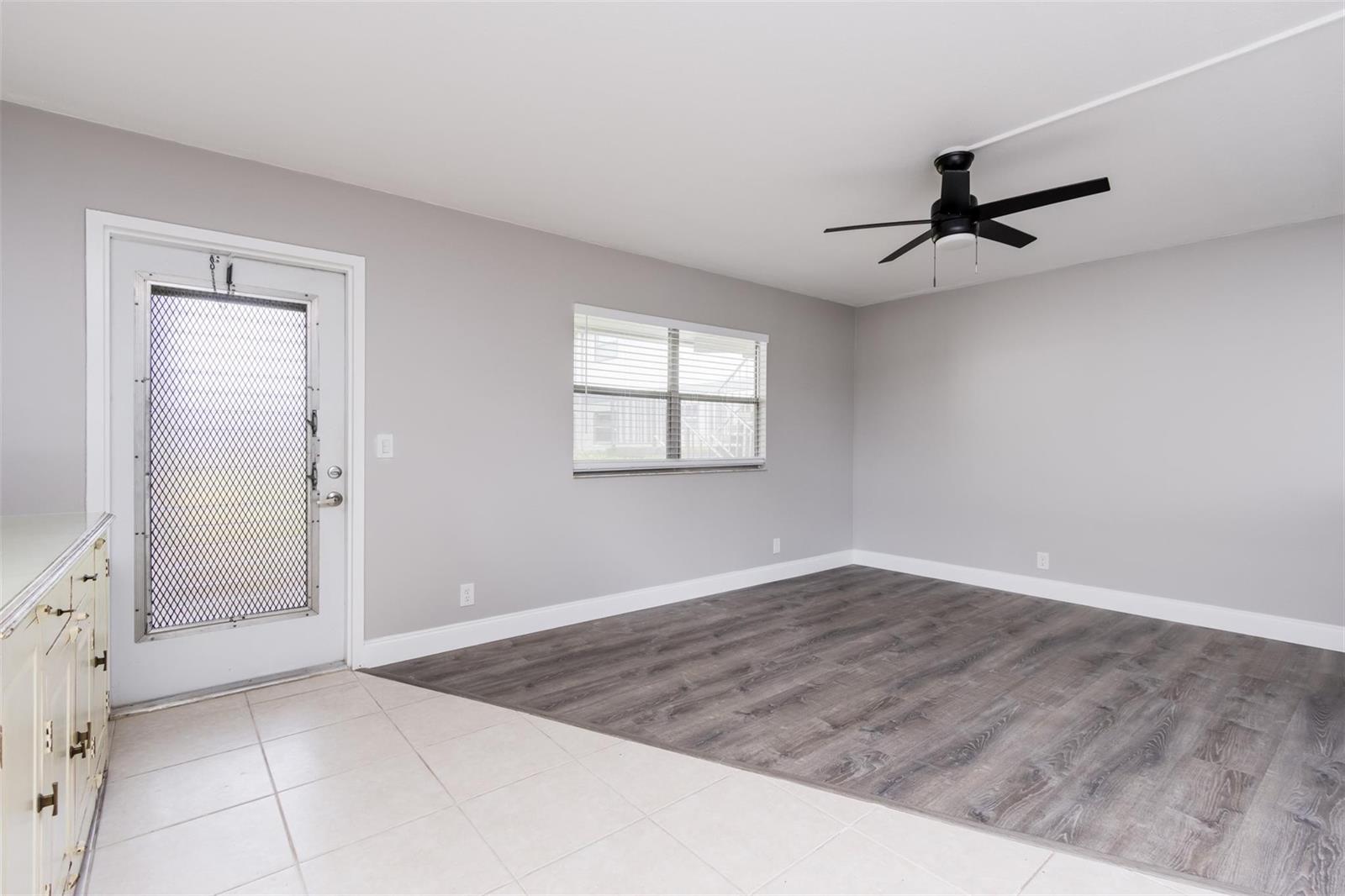 An empty room features gray walls, a ceiling fan, tile flooring, and wood-look laminate flooring — 346 Monaco H # 346, Delray Beach FL 33446, DELRAY BEACH, FL