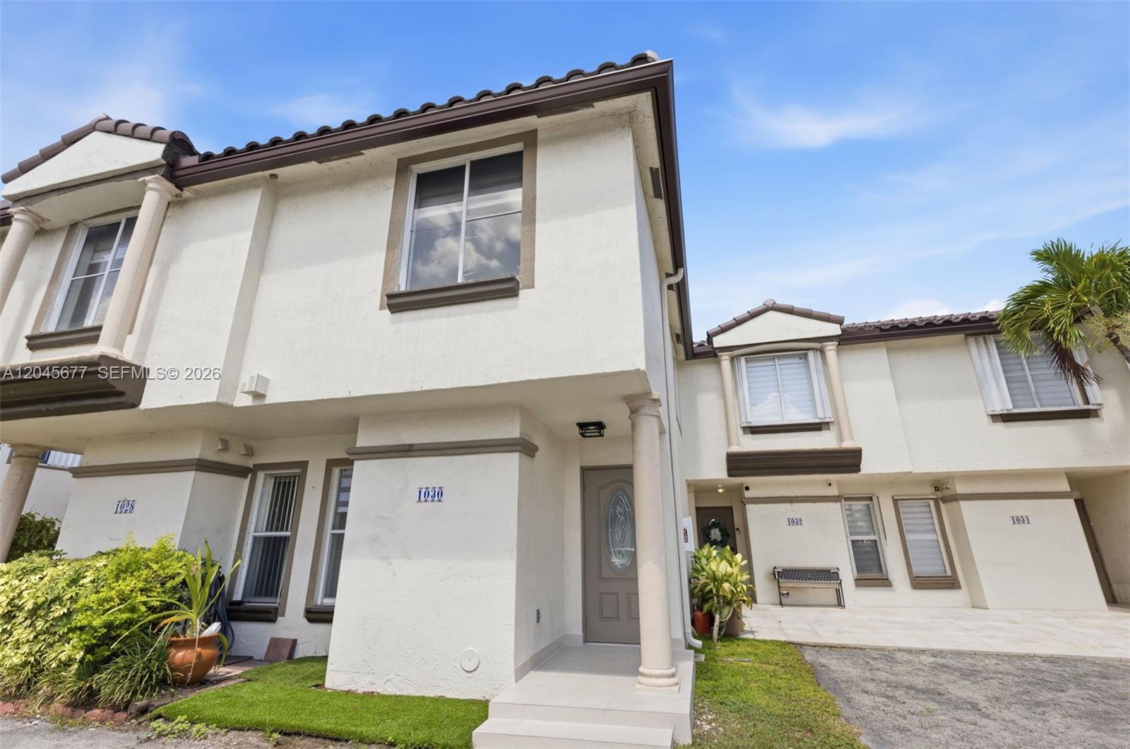 The exterior of a two-story stucco townhouse features a front entrance with a column — 1030 NW 123rd Ct # 706, Miami FL 33182, MIAMI, FL