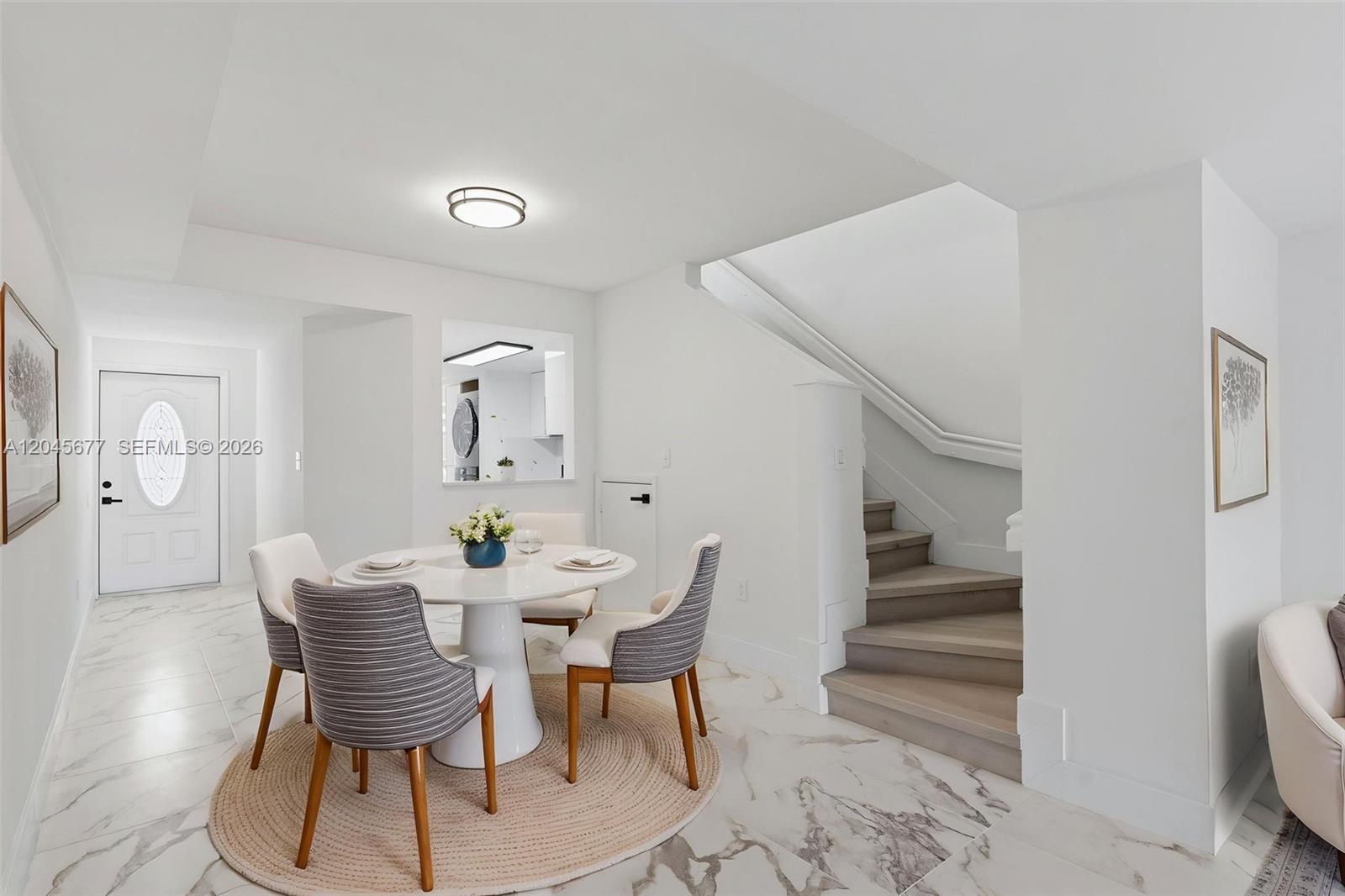 A dining area features a round table, four chairs, marble flooring, and a wooden staircase — 1030 NW 123rd Ct # 706, Miami FL 33182, MIAMI, FL