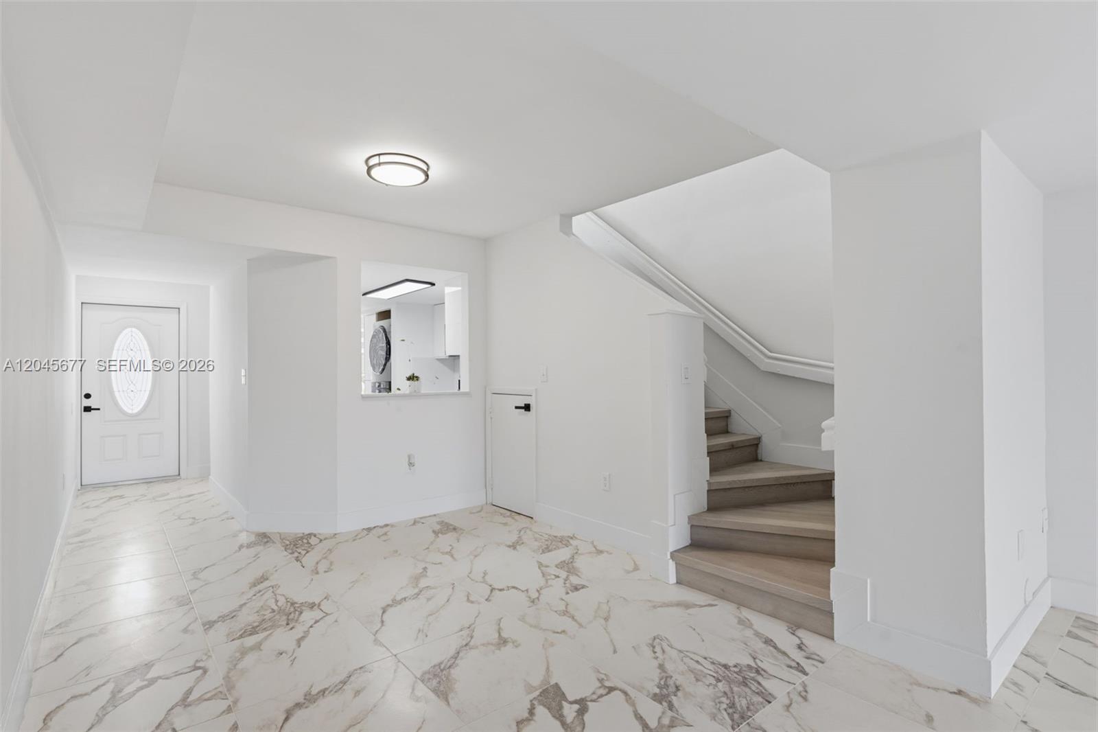 A bright entryway features marble-patterned tile flooring, a white front door, and wooden stairs — 1030 NW 123rd Ct # 706, Miami FL 33182, MIAMI, FL