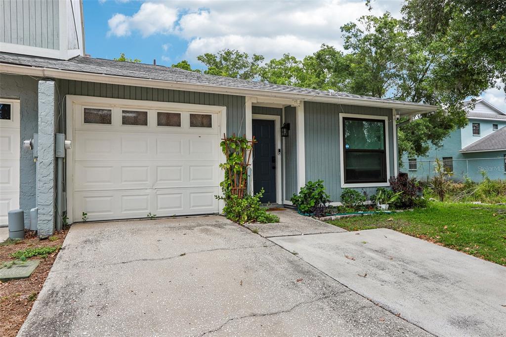A single-story house exterior features a white garage door, a dark blue front door, and siding — 4001 BAINWOOD COURT, TAMPA, FL