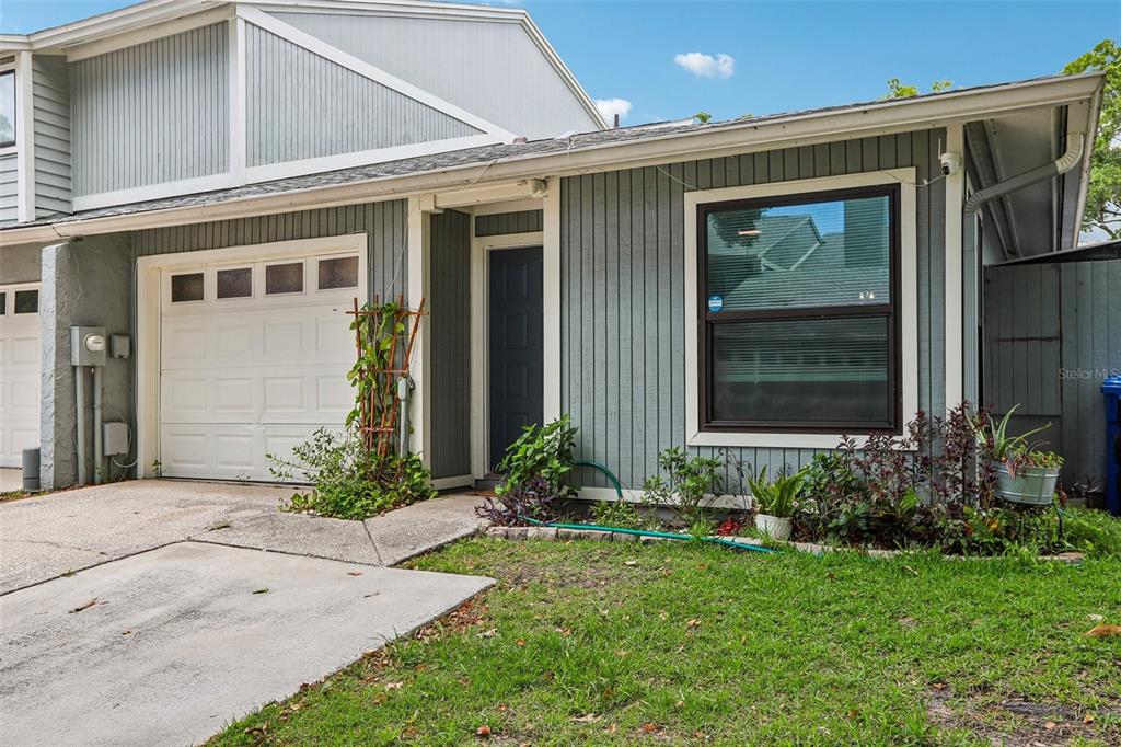 A gray, single-story townhouse with a white garage door and a dark front door — 4001 BAINWOOD COURT, TAMPA, FL