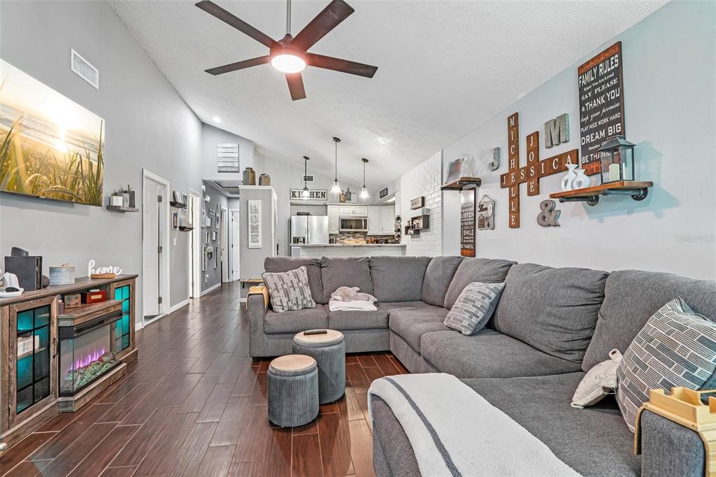 A living room with a gray sectional sofa, dark wood floors, and an open kitchen — 4001 BAINWOOD COURT, TAMPA, FL