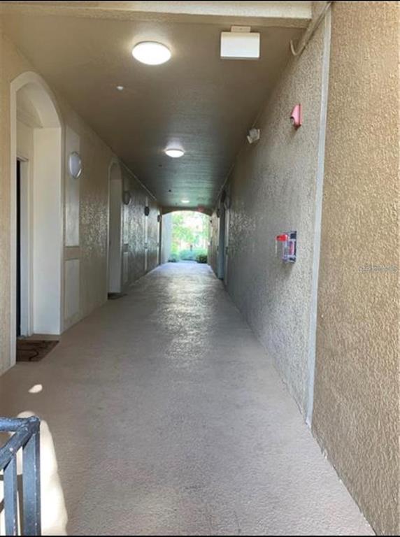 An outdoor covered hallway with beige stucco walls and recessed ceiling lighting — 6466 CAVA ALTA DRIVE UNIT 104, ORLANDO, FL