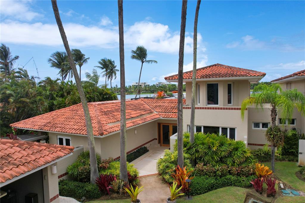 A two-story house with a terracotta tile roof, palm trees, and a landscaped front entrance — 5 THE GREENS VILLAS AT DORADO BEACH, DORADO, PR