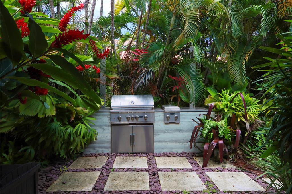 An outdoor kitchen with a stainless steel grill is set among lush tropical landscaping — 5 THE GREENS VILLAS AT DORADO BEACH, DORADO, PR