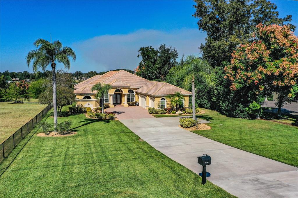 A single-story yellow stucco house with a tile roof and palm trees at sunset — 2918 CLUBHOUSE ROAD, LAKELAND, FL