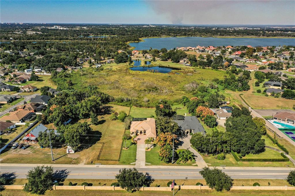 An aerial view shows two houses with pools situated near a lake and wetlands — 2918 CLUBHOUSE ROAD, LAKELAND, FL