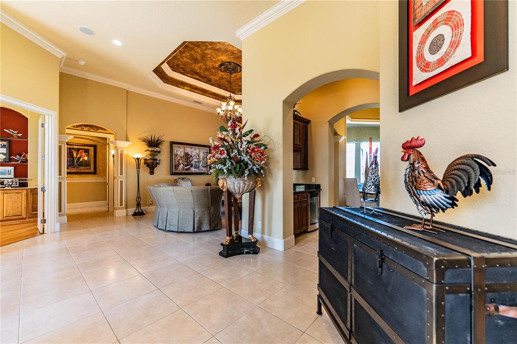A tiled foyer features a rooster statue on a chest and a view into the living area — 2918 CLUBHOUSE ROAD, LAKELAND, FL