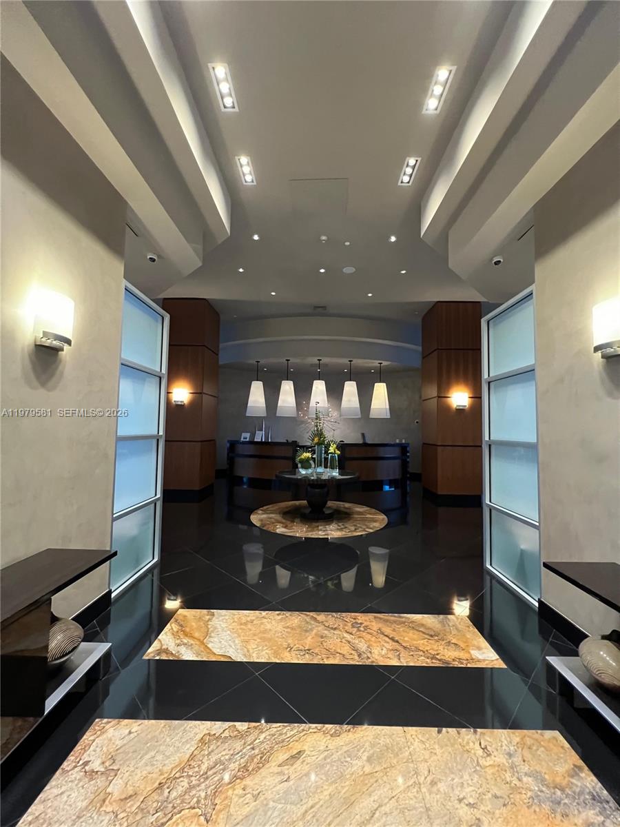 A modern lobby features a dark tiled floor, a central circular table, and a reception desk — 3101 S Ocean Dr # 3102, Hollywood FL 33019, HOLLYWOOD, FL