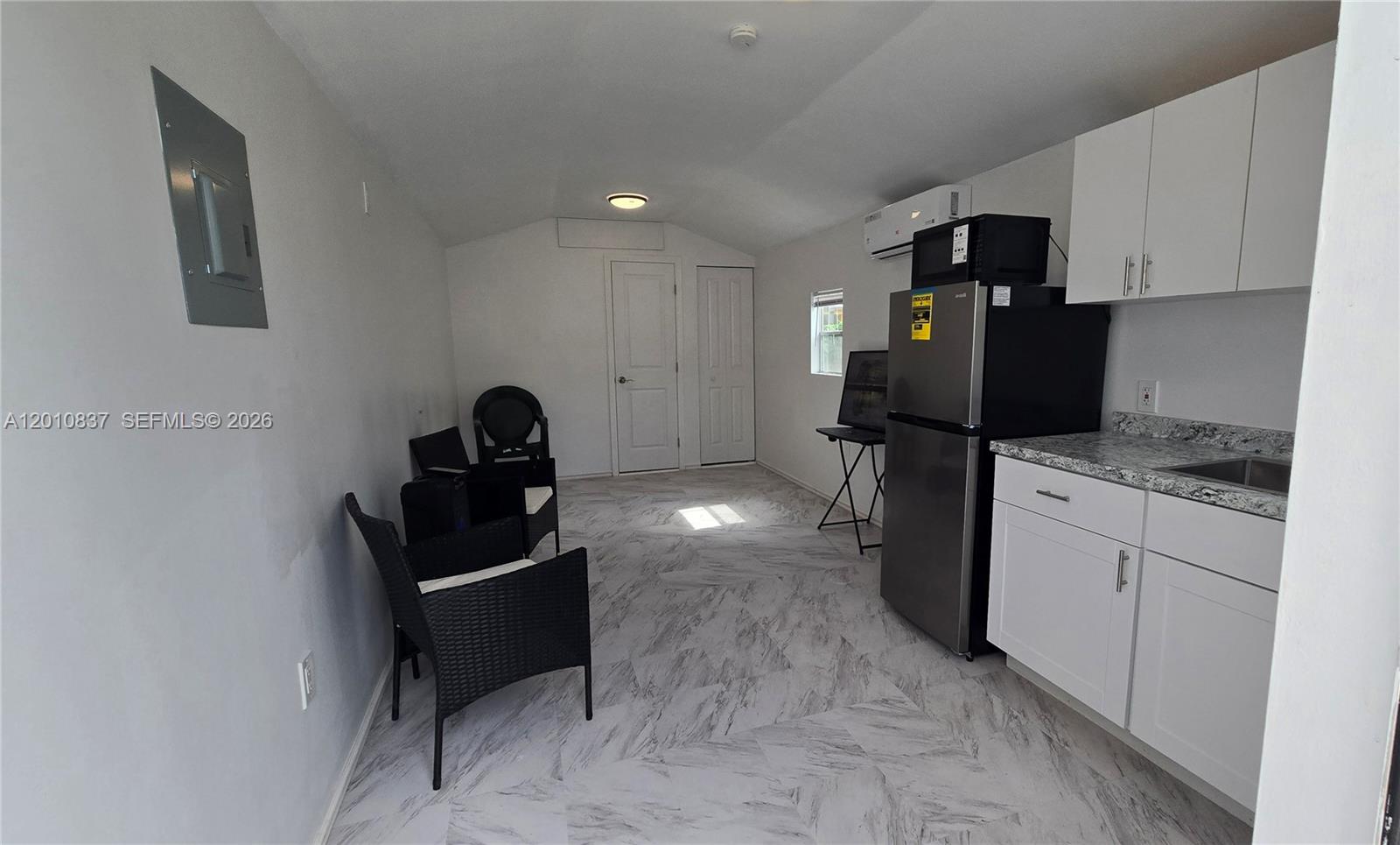This small room features white cabinets, a stainless steel refrigerator, and light-colored tiled flooring — 2440 NW 99th St # A, Miami FL 33147, MIAMI, FL