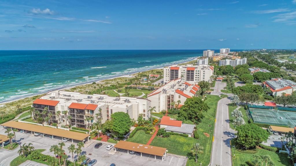 An aerial view of beachfront condominium buildings with parking structures and tennis courts — 1975 GULF OF MEXICO DRIVE UNIT G4-401, LONGBOAT KEY, FL