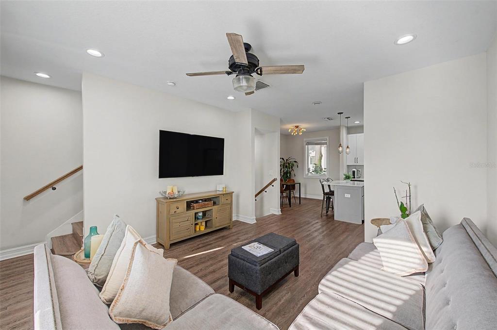 A living room with light wood floors, a grey sofa, and a wall-mounted television — 1527 N MORGAN STREET, TAMPA, FL