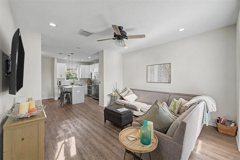 An open-concept living room and kitchen featuring wood-look flooring, a gray sofa, and island seating — 1527 N MORGAN STREET, TAMPA, FL