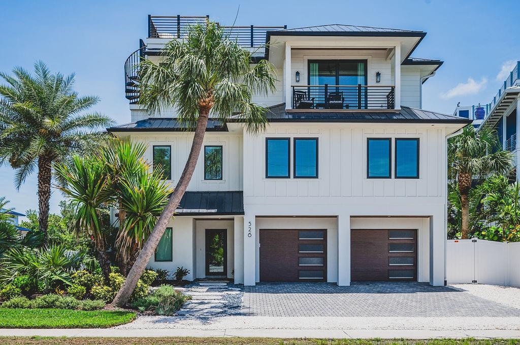 A three-story white house with a two-car garage, balconies, and a palm tree out front — 526 SEAGULL WAY, ANNA MARIA, FL