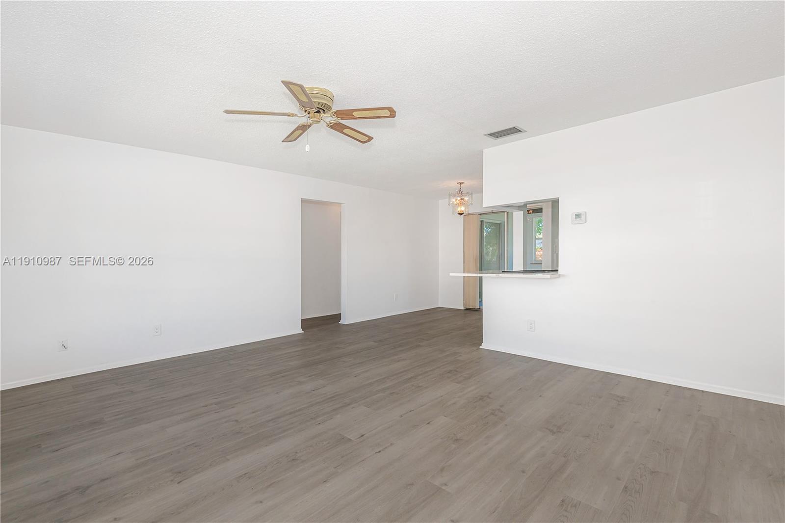 An empty living room features white walls, gray wood-look flooring, and a ceiling fan — 340 Leisure Blvd, Pompano Beach FL 33064, POMPANO BEACH, FL