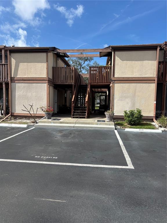 An exterior view of a two-story apartment building with wooden stairs and a parking lot — 5026 WATER OAK DRIVE UNIT 104, BRADENTON, FL