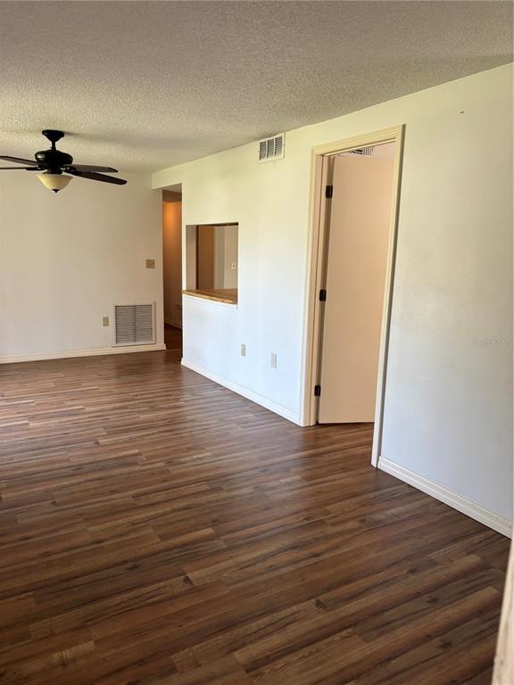 A room with wood-look flooring, a ceiling fan, and a pass-through window to another area — 5026 WATER OAK DRIVE UNIT 104, BRADENTON, FL