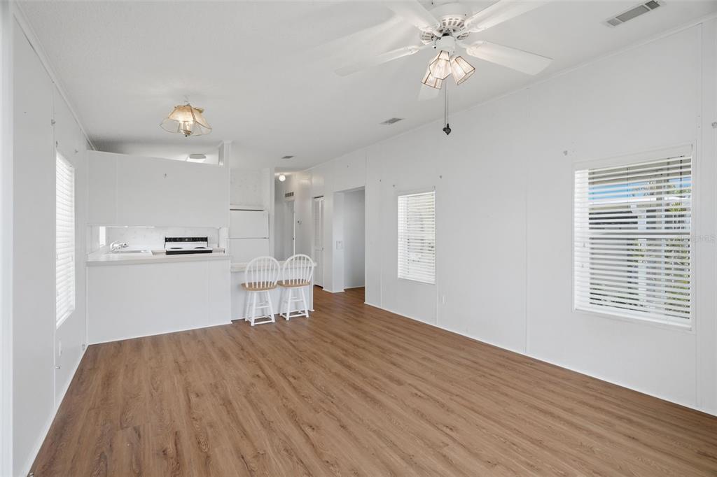 A bright, virtually staged living and dining area with white walls and wood-look flooring — 6826 MOUNT ORANGE DRIVE NE UNIT 383, ST PETERSBURG, FL