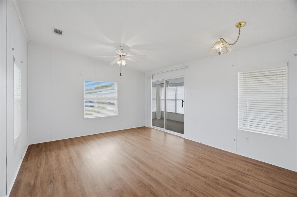 A bright living room with wood-look flooring, white walls, and an open kitchen area — 6826 MOUNT ORANGE DRIVE NE UNIT 383, ST PETERSBURG, FL