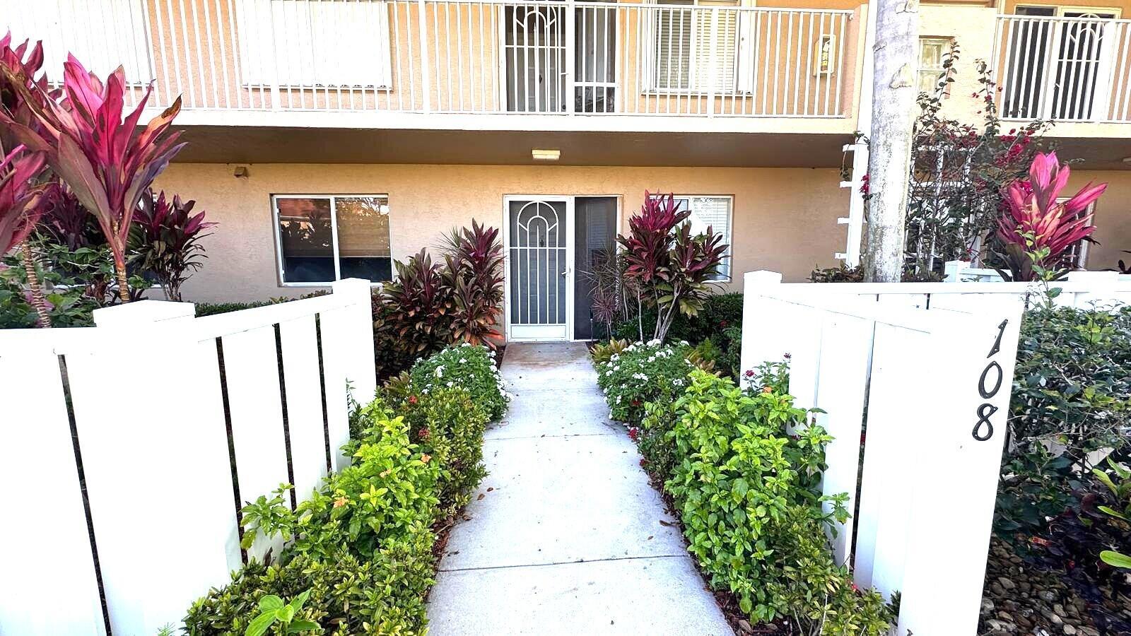 A concrete walkway leads to the front entrance of a two-story residential building — 5876 Regal Glen Drive # 108, Boynton Beach FL 33437, BOYNTON BEACH, FL