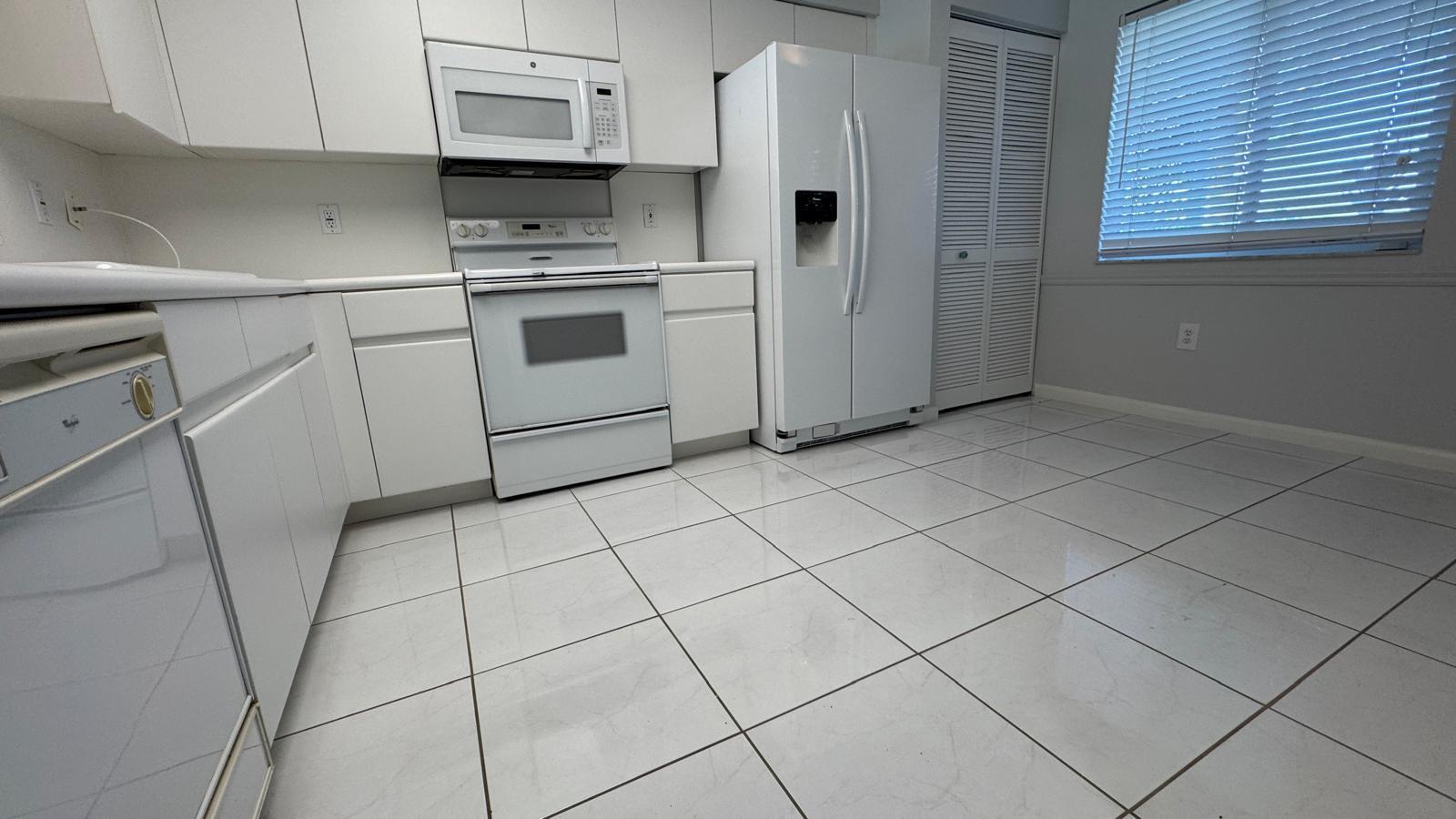 A white kitchen features tiled floors, white cabinetry, and matching appliances — 5876 Regal Glen Drive # 108, Boynton Beach FL 33437, BOYNTON BEACH, FL