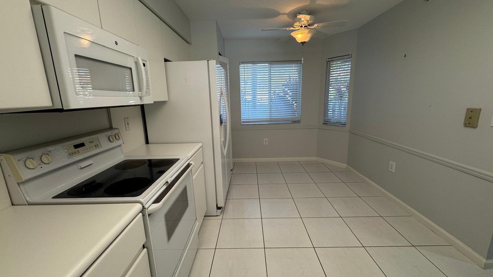 A kitchen with white appliances, white cabinets, and white tile flooring — 5876 Regal Glen Drive # 108, Boynton Beach FL 33437, BOYNTON BEACH, FL