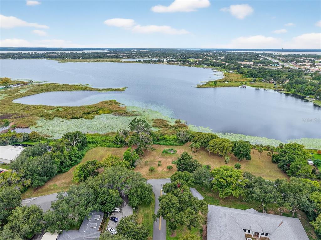 An aerial view shows a grassy lot situated along the shore of a large lake — AMVETS WAY, MOUNT DORA, FL