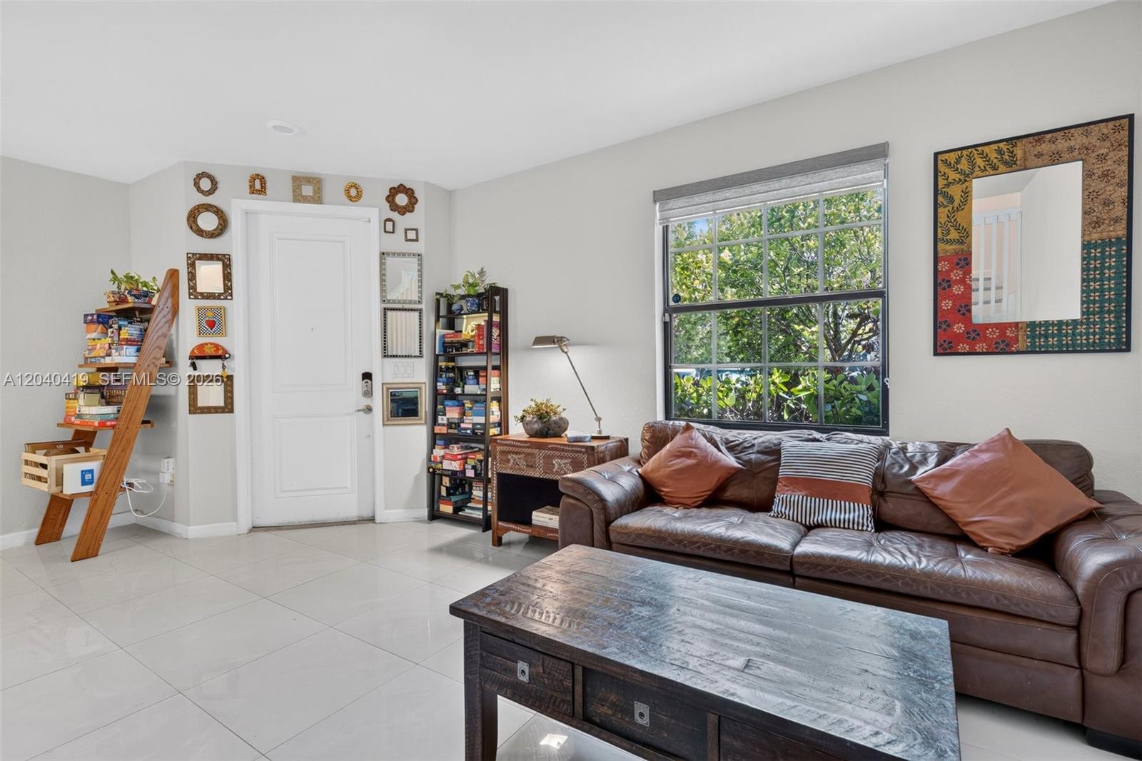 A living room features a brown leather sofa, a wooden coffee table, and a gallery wall — 11418 SW 250th St, Homestead FL 33032, HOMESTEAD, FL